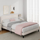 Neatly made bed with pink and gray bedding in a bedroom setting.