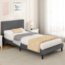 Gray upholstered bed with white bedding and beige pillows in a bedroom setting.